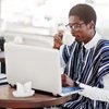 African man traditional clothes glasses sitting outdoor caffe drink coffee working laptop 627829 2327