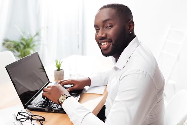 Portrait smiling african american businessman white shirt sitting happily looking camera while working his laptop office isolated 574295 3254 %281%29