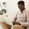 Handsome cheerful young dark skinned male smm manager enjoying working from home sitting sofa with laptop computer 343059 4118